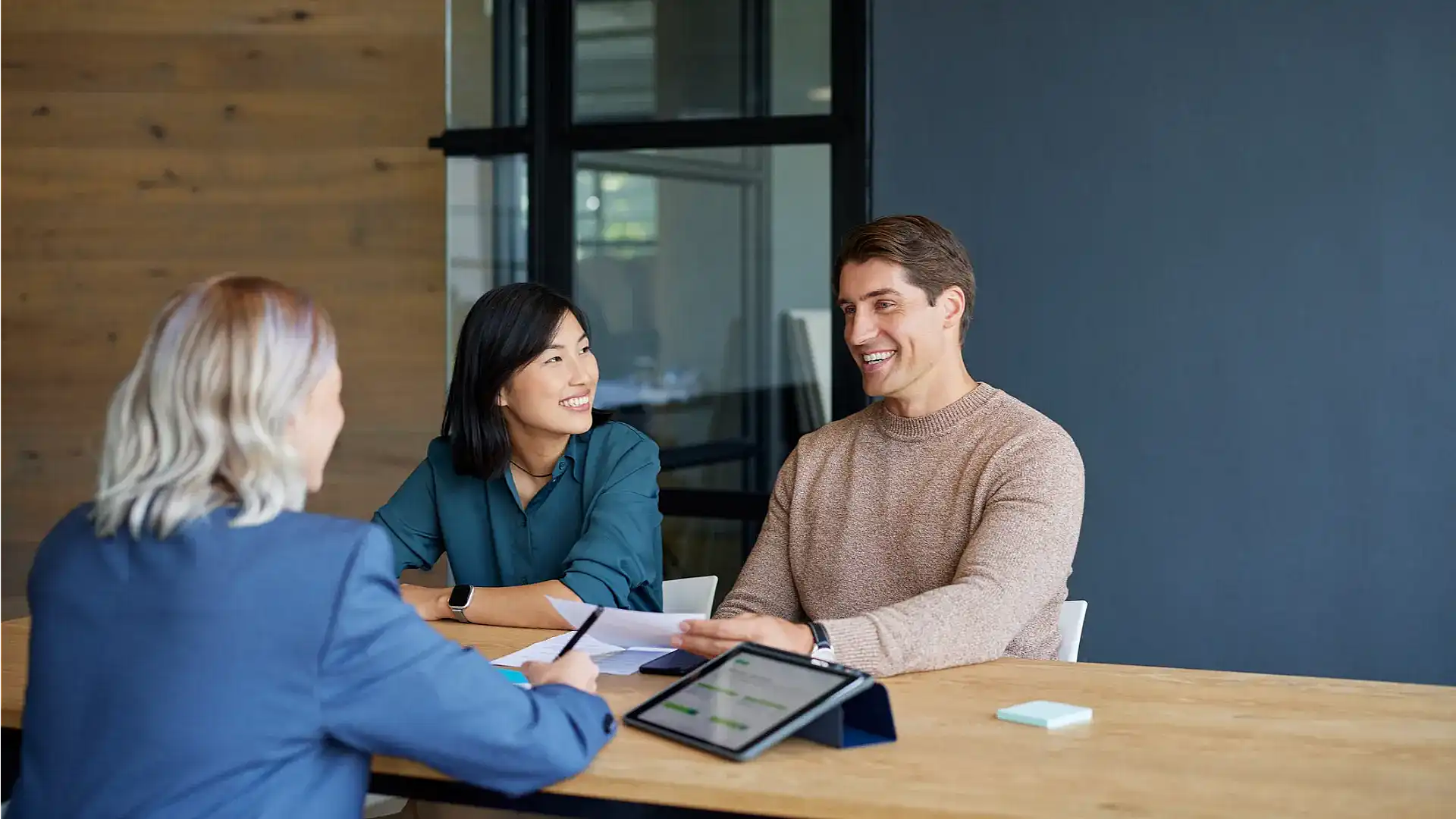 Mortgage adviser meeting with clients reviewing compliance notes, financial documents and regulatory requirements during a professional consultation.